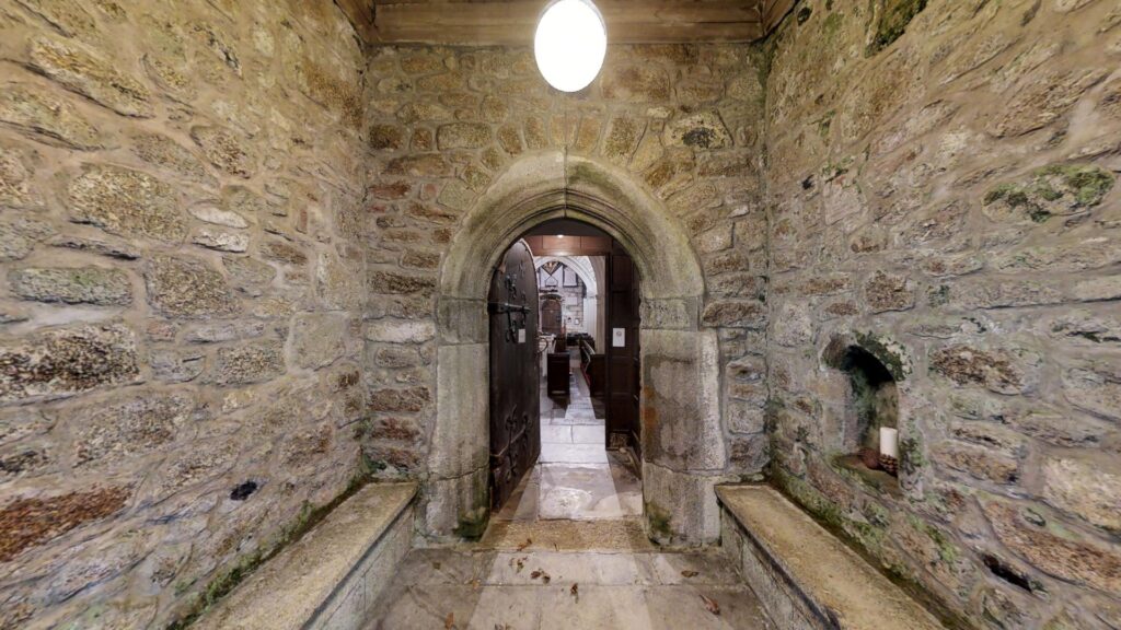 grantie arched entrance into Madron church with light over the top.