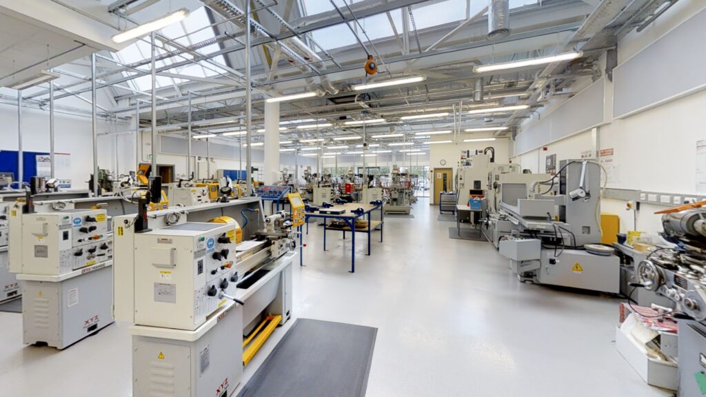 Image shows a college machine shop training room filled with various lathes and CNC machines etc.