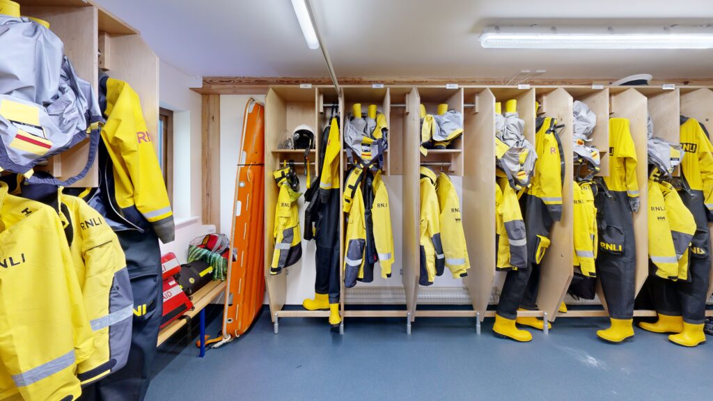 a crew room of the RNLI Penlee lifeboat station with crews equipment hanging up.
