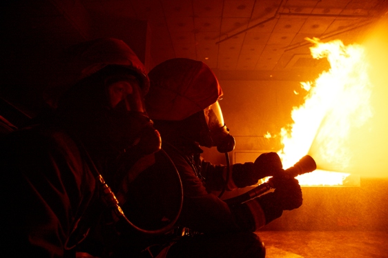 Credit By South Yorkshire Fire & Rescue - Flickr: Firefighter training, CC BY-SA 2.0, https://commons.wikimedia.org/w/index.php?curid=30019341 South Yorkshire Fire and rescue services fighting a fire with a hose and wearing breathing apparatus.