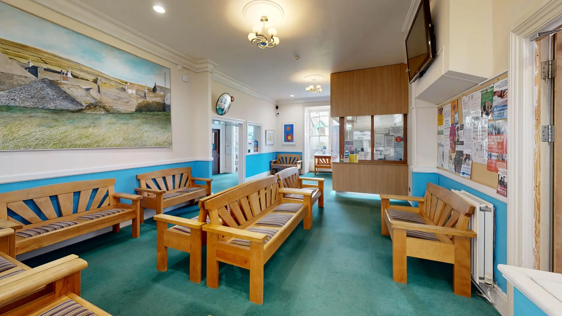A doctors surgery waiting room showing wooden benches with cushioned seating.